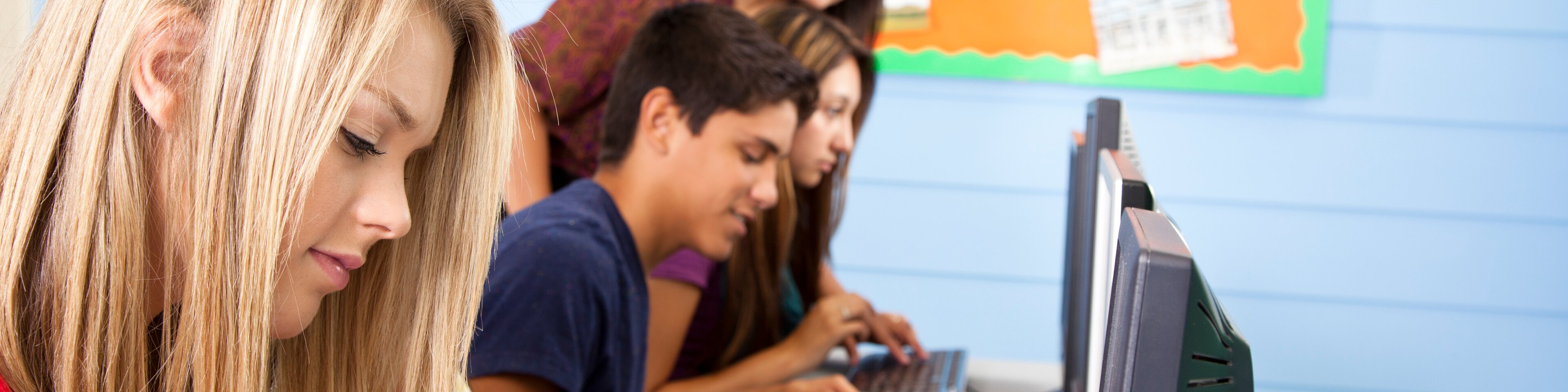 Schüler sitzen vor einem Bildschirm und tippen etwas auf der Tastatur ein | © fstop123 - Getty Images/iStockphoto